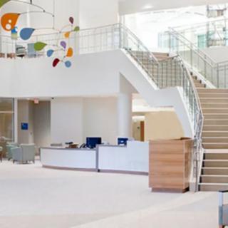A modern office lobby with a reception desk and staircase.