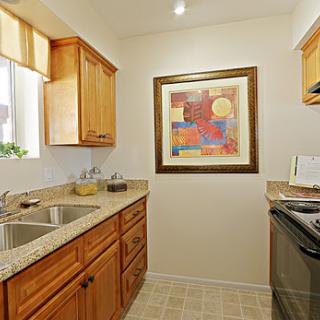 A cozy kitchen featuring wooden cabinets, modern appliances, and colorful artwork.