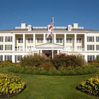 A historic building with a well-maintained garden and an American flag flying prominently.