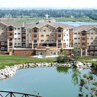 A picturesque view of a residential building beside a tranquil pond.