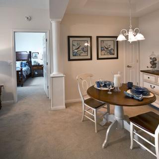 A cozy dining area with a wooden table and chairs, decorated with artwork and warm lighting.