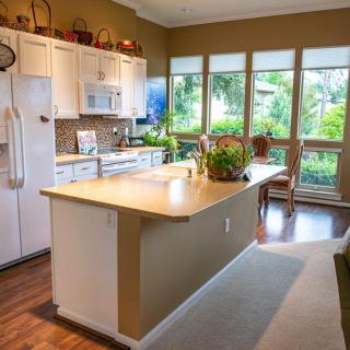 A bright and spacious kitchen with an island, large windows, and wooden flooring.