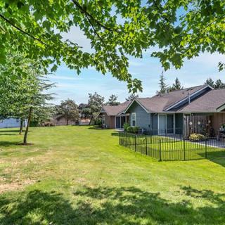 A peaceful suburban house with a spacious lawn and trees under a sunny sky.