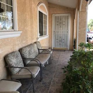 A cozy front porch with chairs and plants along a tiled walkway.