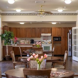A cozy kitchen and dining area with wooden cabinets and a round dining table adorned with flowers.