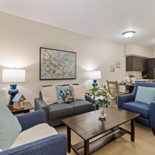 Cozy living room with blue and neutral-toned furniture, adorned with artwork and decorative elements.