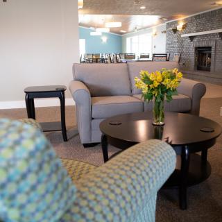 A cozy living room featuring a sofa, coffee tables, and a vase of yellow flowers.