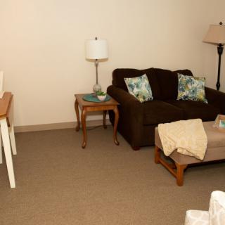 A cozy living room with a dark sofa, decorative pillows, side tables, and lamps.