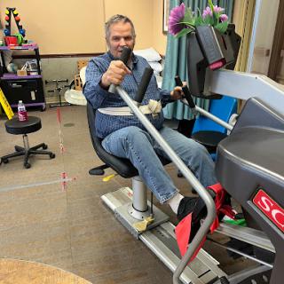 A man engaging in a workout session on a rowing machine, emphasizing rehabilitation and fitness.