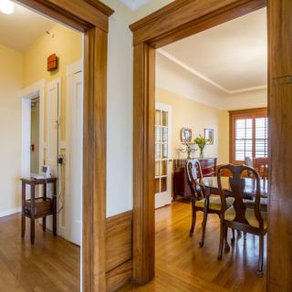 A traditional dining room with wood flooring and elegant furniture viewed through a doorway.