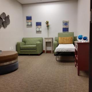 A cozy room with a green chair, sofa, decorative artwork, and a small table with ornaments.