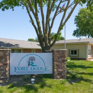 A sign for Fort Dodge Rehabilitation Center in front of a building surrounded by greenery.