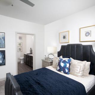 A modern bedroom with stylish decor, featuring a black upholstered bed and elegant artwork.