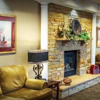 A cozy living room with a stone fireplace, comfortable seating, and decorative artwork.