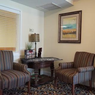 A cozy corner featuring two striped chairs and a wooden table, adorned with artwork on the wall.