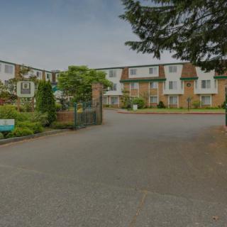 A residential apartment complex with landscaped surroundings and a parking area.