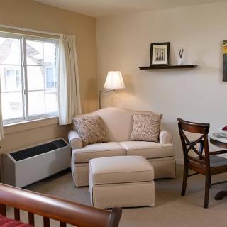 Cozy living room corner with an armchair, ottoman, and soft lighting.
