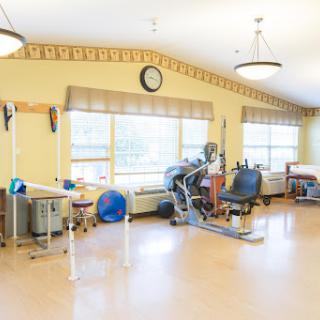 A well-lit therapy room equipped with various exercise machines and tools for rehabilitation.