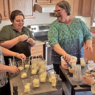 A group of people enjoying making ice cream together in a kitchen.