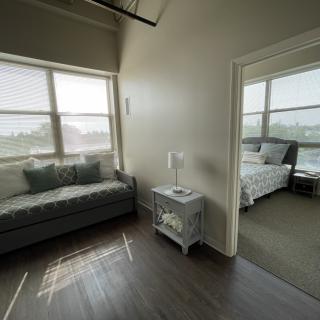 A cozy living space featuring a sofa and adjacent bedroom with ample natural light.