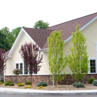 A beautifully landscaped residential house with trees and a well-maintained garden.