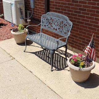 A decorative bench surrounded by potted flowers and an American flag.