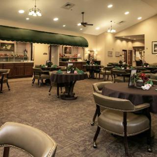 A well-arranged dining area featuring tables and chairs, illuminated by warm lighting.