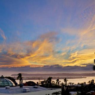 A vibrant sunset with colorful clouds above a scenic landscape featuring palm trees.