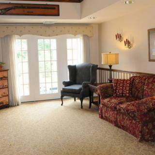 A cozy living room with a floral sofa, armchair, and bright natural light coming through French doors.