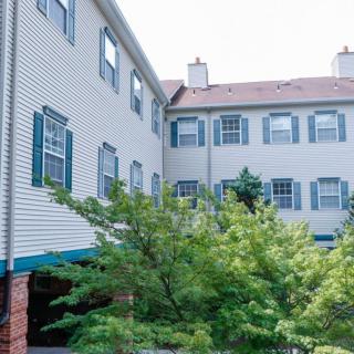 A residential building with multiple windows and greenery in the foreground.