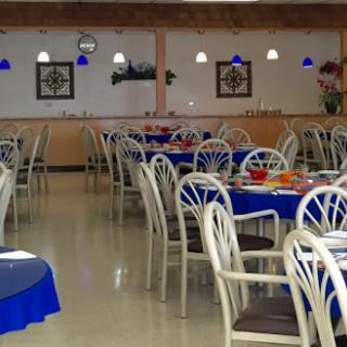 A spacious restaurant interior featuring blue tablecloths and comfortable seating arrangements.