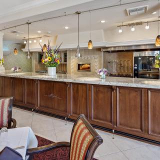 A stylish restaurant interior featuring a bar counter, seating area, and open kitchen.