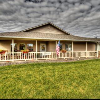 A charming residential house with a welcoming porch and vibrant landscaping under a cloudy sky.