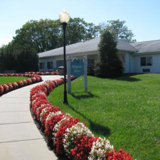 A well-maintained building with a flower-lined pathway on a sunny day.