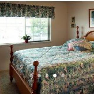 A cozy bedroom with a large bed, floral quilt, and a window with matching curtains.