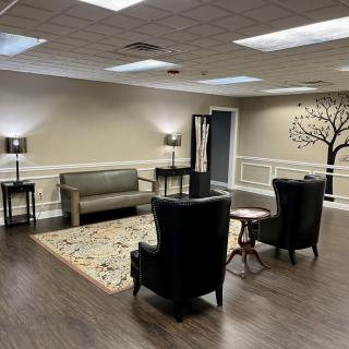A cozy waiting room with comfortable seating, soft lighting, and a decorative tree mural on the wall.