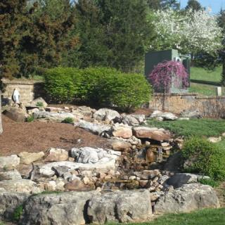 A beautifully landscaped garden with rocks, greenery, and colorful flowers.