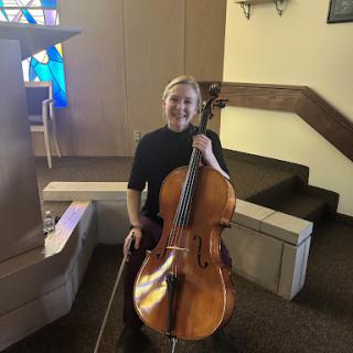 A talented cellist posing with their instrument in a beautiful church setting.