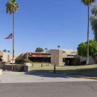 A sunny day at a hospital entrance with palm trees and an American flag.