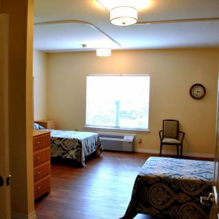 A spacious bedroom with two twin beds, a dresser, and a large window.