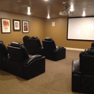 A cozy home theater room with comfortable seating and a large screen.