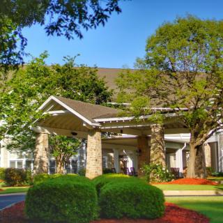 A picturesque view of a building's entrance surrounded by lush greenery.