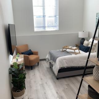 A cozy bedroom with modern decor, featuring a bed, armchair, and decorative elements.