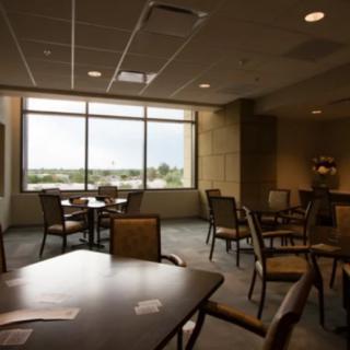 A quiet lounge area with several tables and chairs, featuring large windows that let in natural light.
