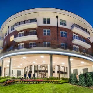 A modern hotel building beautifully lit up at night with well-maintained landscaping.