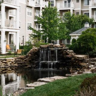 A serene waterfall and pond located in the landscaped grounds of a residential apartment complex.