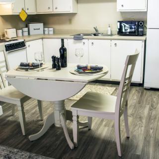 A cozy kitchen features a small dining table set for two, complete with wine and elegant place settings.