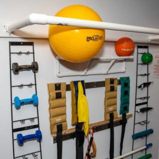 A home gym setup with various fitness equipment organized on a wall.