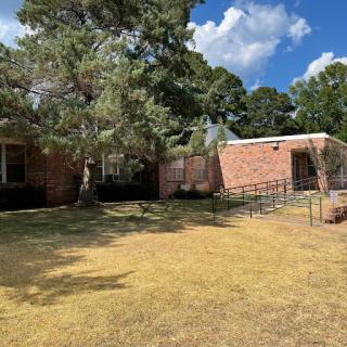 A brick building surrounded by grass and trees under a blue sky.