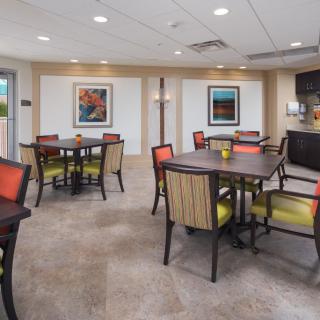 A modern dining area with neatly arranged tables and chairs, complemented by artwork on the walls.